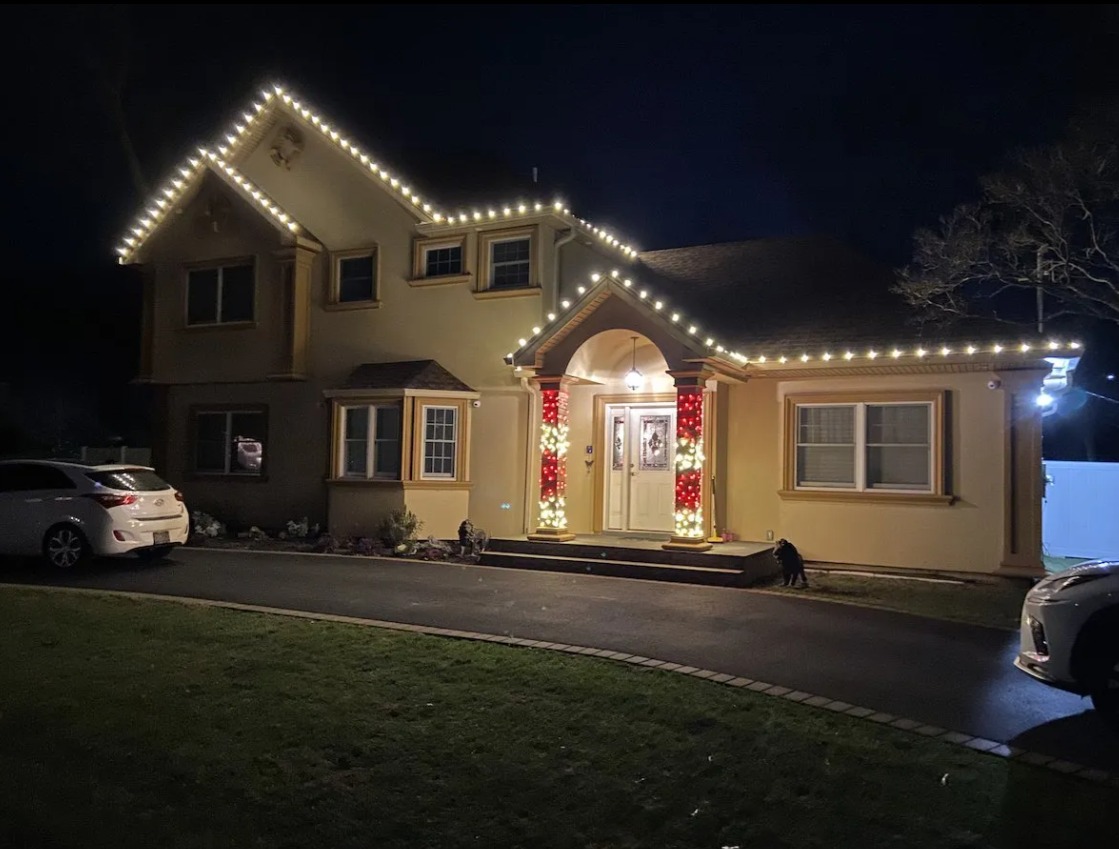 A home with warm white roofline lights and red and white entryway columns